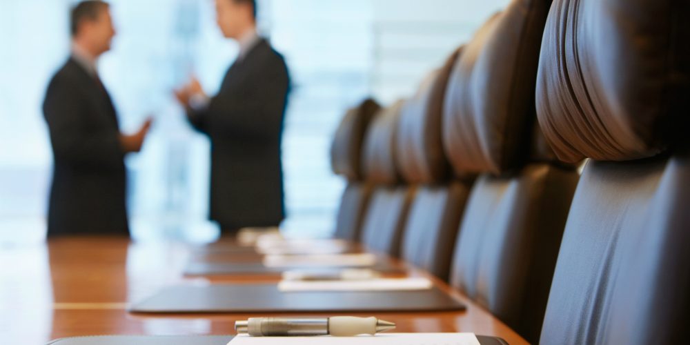 shutterstock_144792676-Side-view-of-two-blurred-businessmen-talking-in-conference-room-web